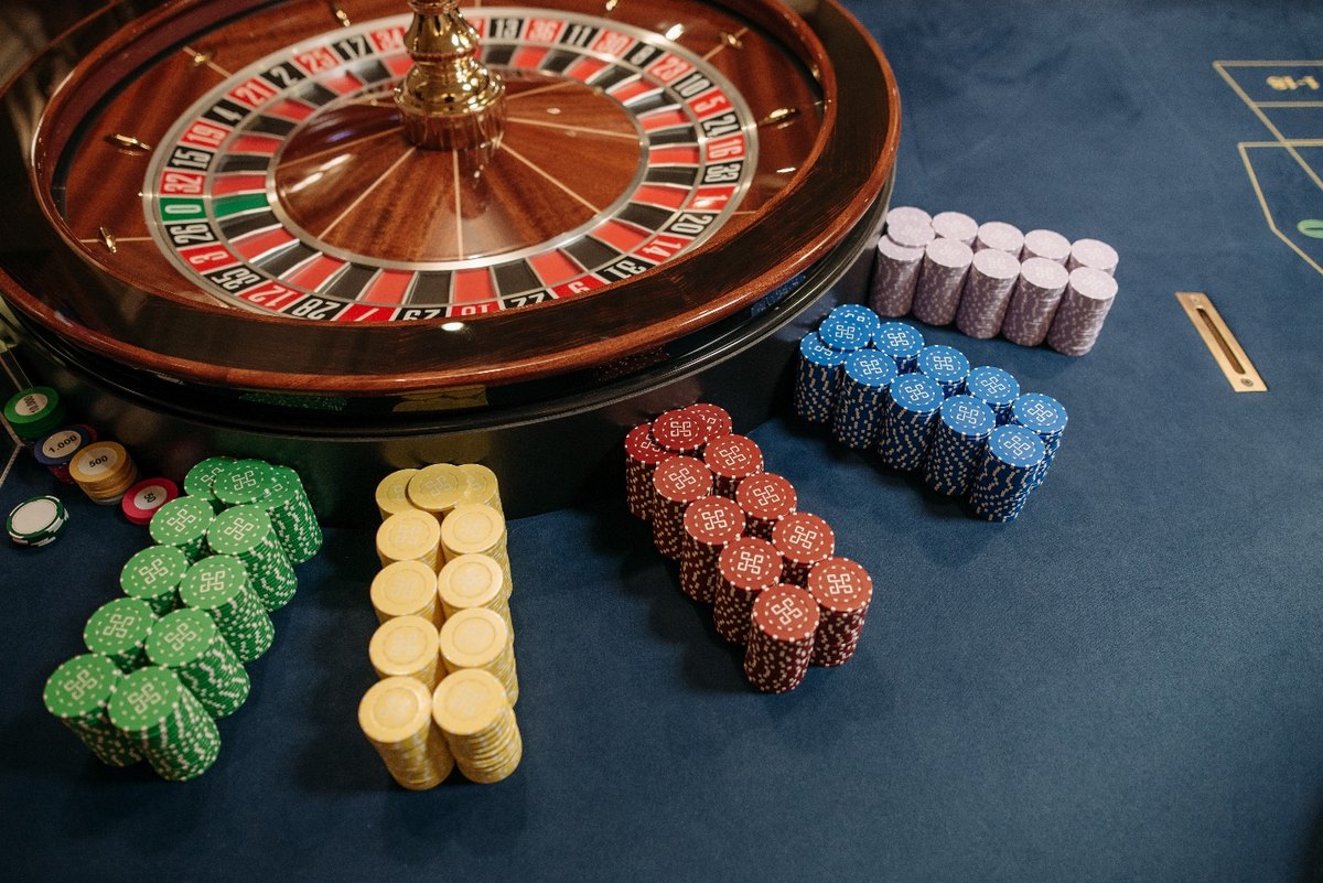 Close Up Photo of Stacked Poker Chips Beside Casino Roulette (Source: Pexels.com)